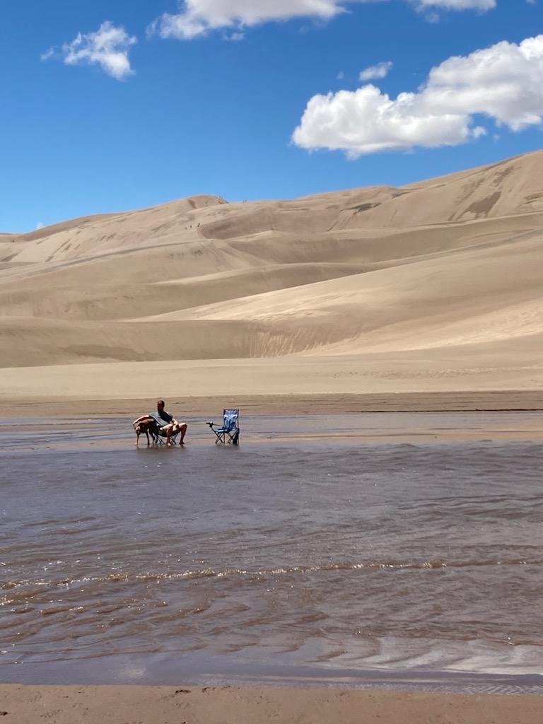 Gabe with his feet in the sand with his dog, Nyx