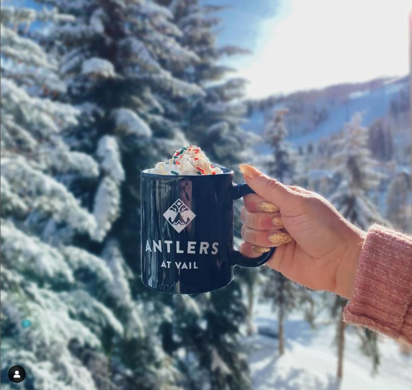 Antlers coffee mug with backdrop of snowy mountains