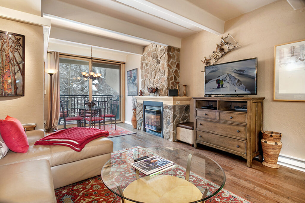 Living and dining area of Antlers at Vail condo 308, with gas fireplace and large windows to the river