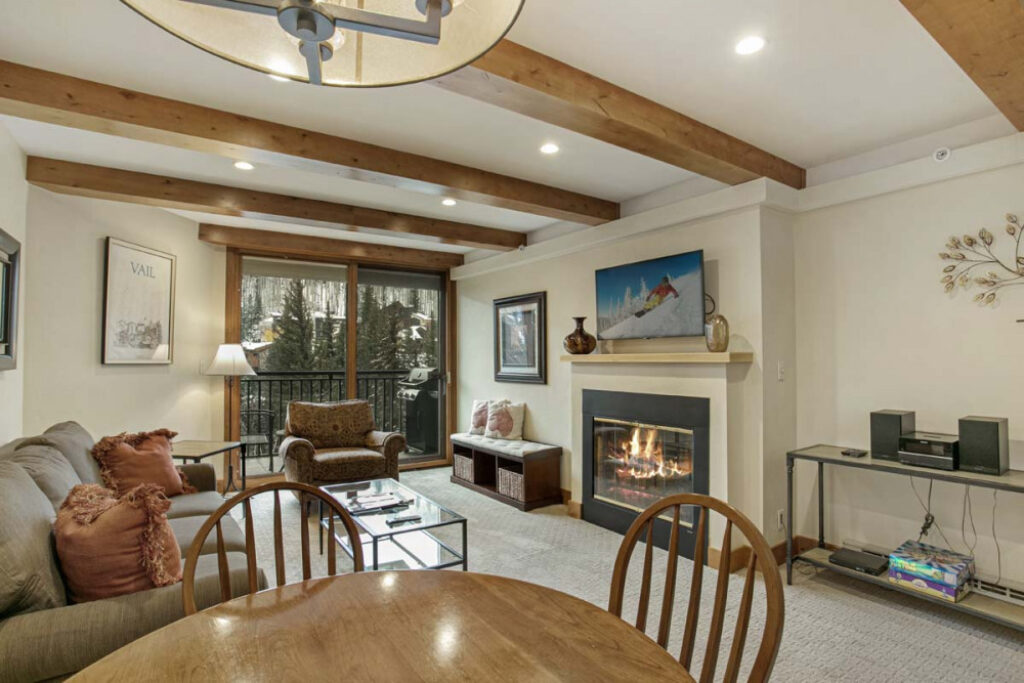 Dining and living space of Antlers at Vail condo #504, with cozy gas fireplace and large windows overlooking Gore Creek