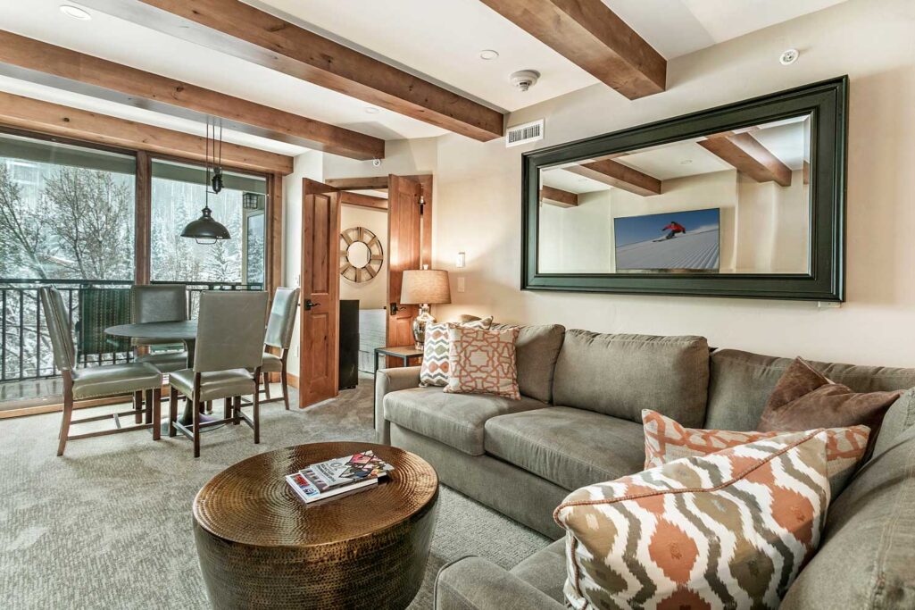 Living and dining areas of Antlers at Vail condominium 507 with large glass sliding doors overlooking the creek