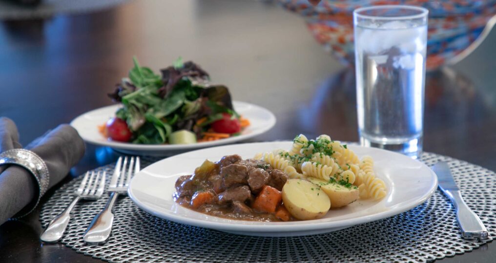 plated beef, potatoes and pasta with a salad