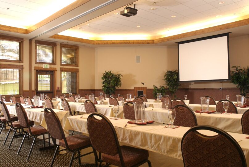 Tables and chairs set classroom style in conference room with projector screen down