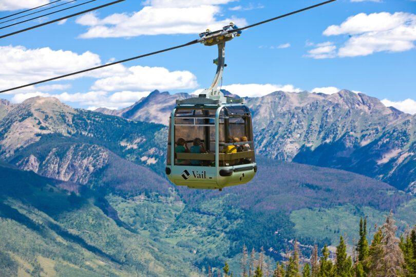 Gondola taking guests up to the top of Vail Mountain in the summer with gore range as the backdrop