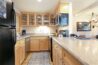 Fully equipped kitchen in Antlers at Vail condo 502 featuring maple cabinets with glass fronts, granite countertops, black refrigerator, and stainless steel appliances