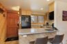 Entry and kitchen bar area of Antlers at Vail condo 502 with granite breakfast bar, bar stools, black refrigerator, and ski storage near the front door