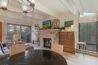 Living room of Antlers at Vail condo 502 showcasing a lit stone fireplace, wall-mounted TV, exposed beam ceiling, and sliding glass doors to the balcony