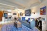 Spacious open living area in Antlers at Vail condo 502 with gray sofa, blue kilim rug, kitchen bar, and mountain artwork on the walls