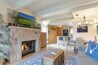 Stone gas fireplace with lit fire in Antlers at Vail condo 502, with barn door, kitchen bar, and open living and dining area in background
