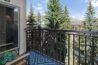 Private balcony of Antlers at Vail condo 502 with outdoor seating overlooking tall evergreen trees and mountain views in summer