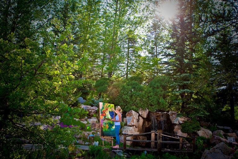 Painter creating artwork in a lush garden setting with waterfall features at Betty Ford Alpine Gardens in Vail, Colorado.