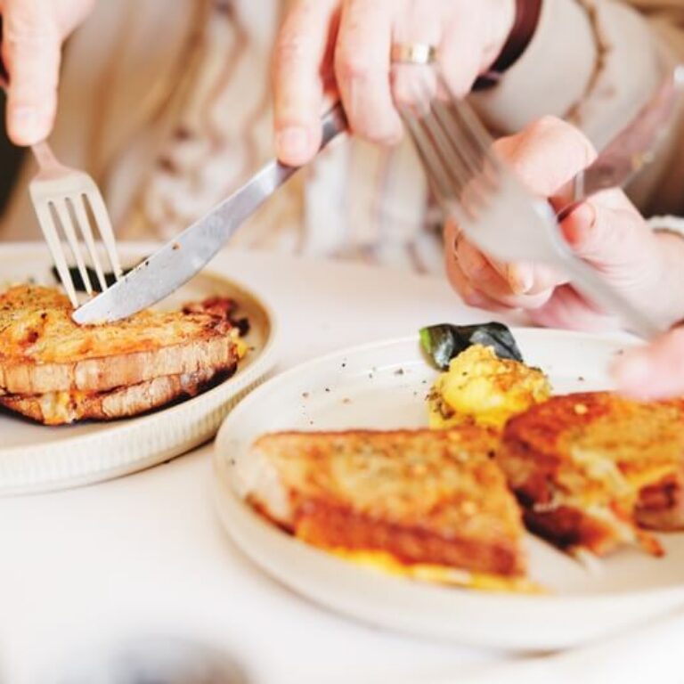 Breakfast plate with French toast, eggs and potatoes being shared at a table.